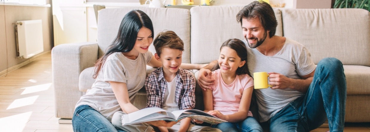 Familie, 2 ouders, 2 kinderen lezen samen in een boek 