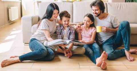 Familie, 2 ouders, 2 kinderen lezen samen in een boek 